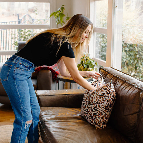 woman fluffing pillow on couch